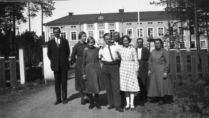En grupp m&auml;nniskor som st&aring;r framf&ouml;r en byggnad.