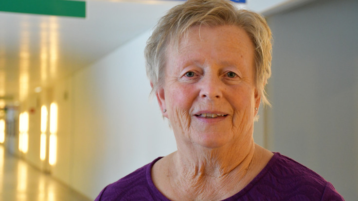 En kvinna i en lila tr&ouml;ja som st&aring;r i en korridor.