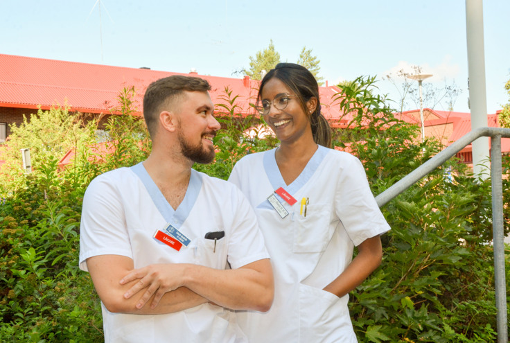Jakub och Shanie, iklädda arbetskläder, utanför hälsocentralen.