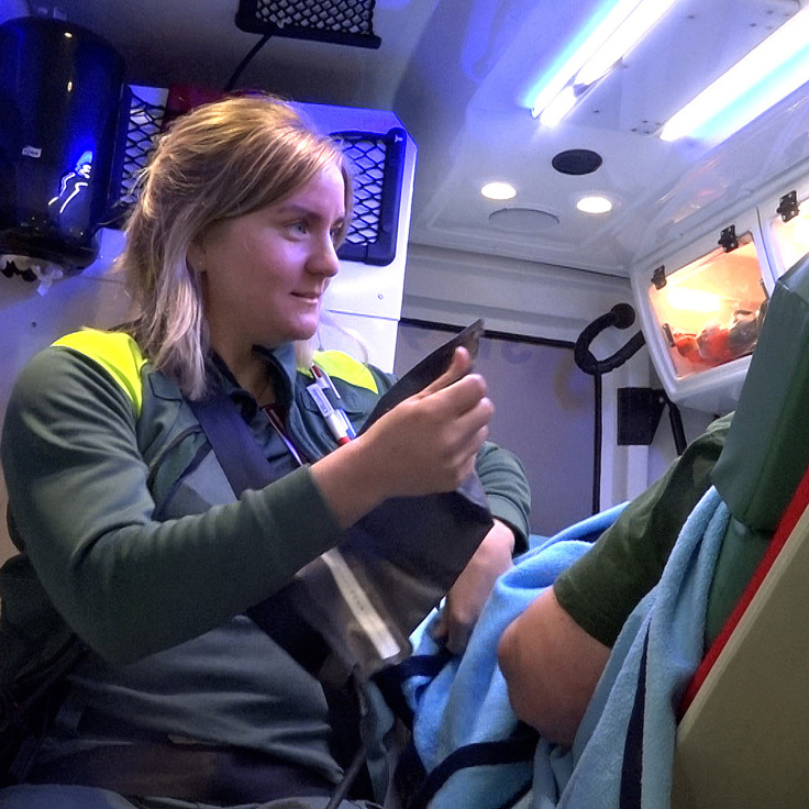Ambulanssjuksköterska som vårdar patient i en ambulans.