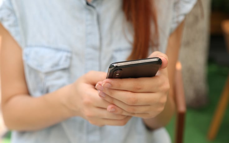 En kvinna som håller en smartphone i händerna.