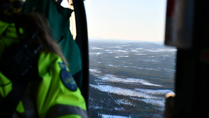 En utsikt inifr&aring;n en helikopter &ouml;ver ett sn&ouml;t&auml;ckt landskap.
