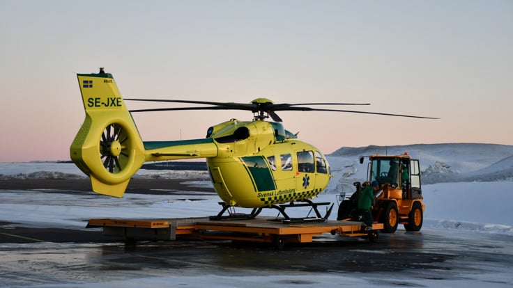 En gul helikopter som st&aring;r p&aring; flygplatsens asfalterade yta.