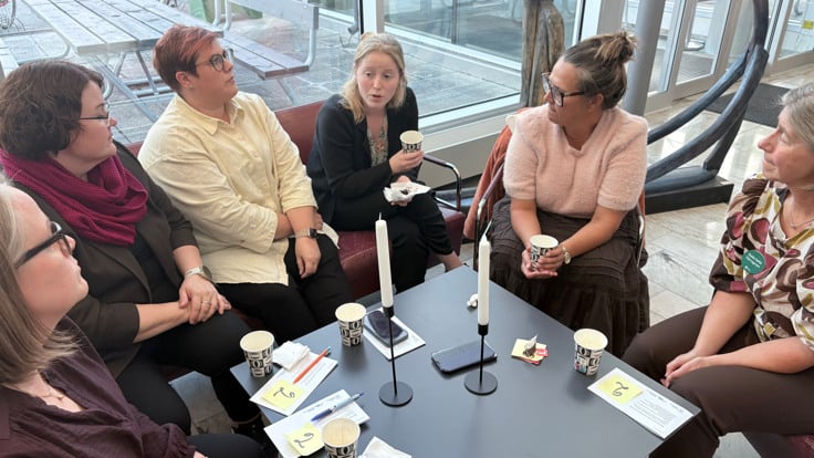 En grupp kvinnor som sitter runt ett bord och pratar.