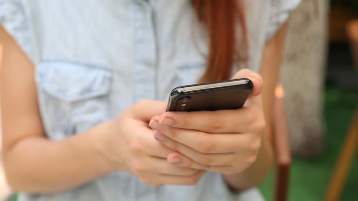 En kvinna som håller en smartphone i händerna.