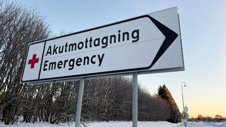 En gatuskylt p&aring; en sn&ouml;ig v&auml;g med tr&auml;d i bakgrunden.