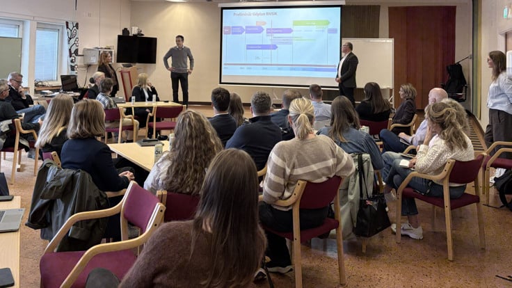 En grupp m&auml;nniskor som sitter p&aring; stolar framf&ouml;r en projektorsk&auml;rm.