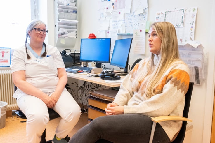 Tv&aring; kvinnor som sitter vid ett skrivbord framf&ouml;r datorer.