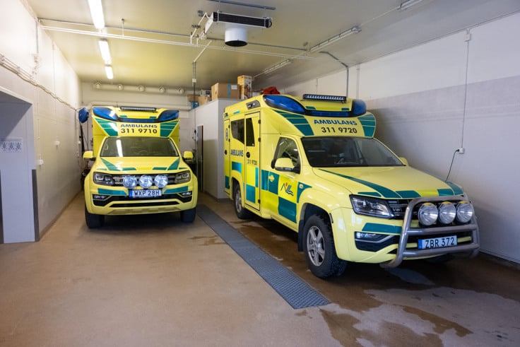 Tv&aring; ambulanser som st&aring;r parkerade i ett garage.