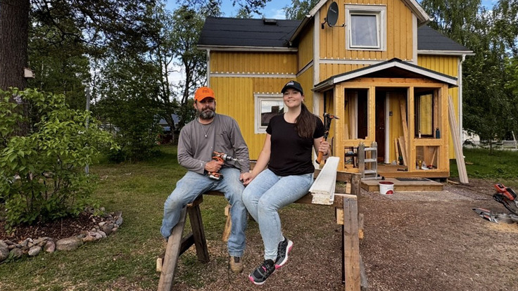Tv&aring; personer som sitter p&aring; en b&auml;nk framf&ouml;r ett hus.