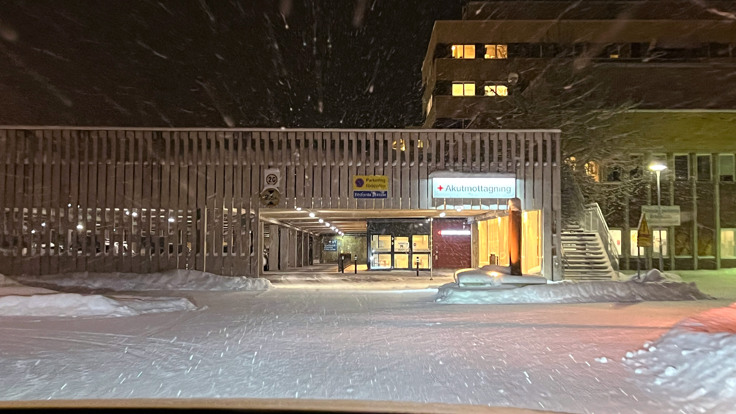 En sn&ouml;ig natt utanf&ouml;r en byggnad med en parkeringsplats framf&ouml;r sig.