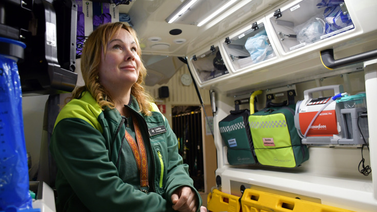 En kvinna i en gr&ouml;n jacka som sitter i en ambulans.