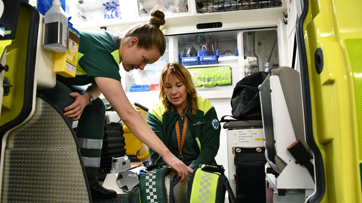 Tv&aring; kvinnor i gr&ouml;na tr&ouml;jor som lastar in bagage.