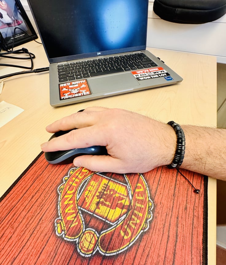 En hand som h&aring;ller i en datamus. Manchester united &auml;r tryckt p&aring; musmattan.