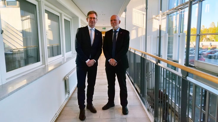 Två män i kostym som står bredvid varandra.