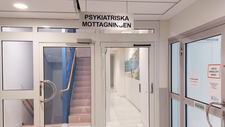 En vit byggnad med tv&aring; d&ouml;rrar och en skylt p&aring; d&ouml;rren.