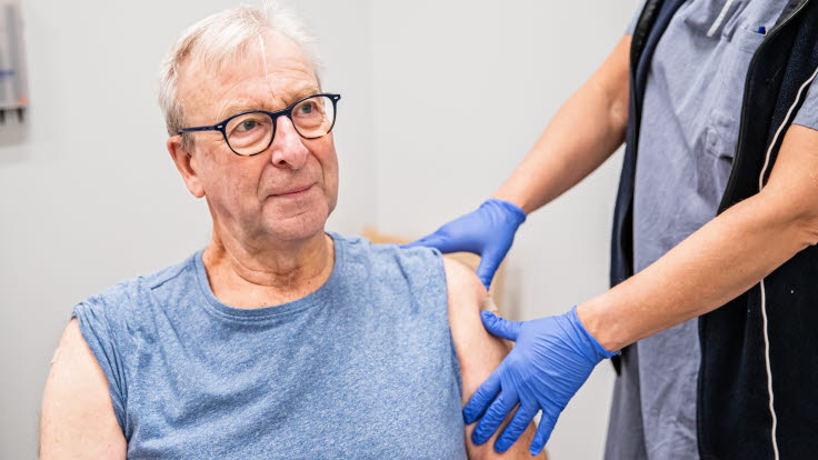 Äldre person som får vaccin i armen.
