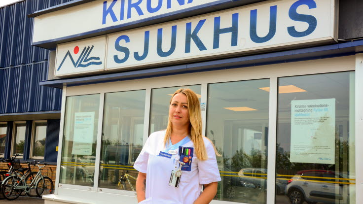 Vedrana står framför entrén till Kiruna sjukhus iklädd vita personalkläder.