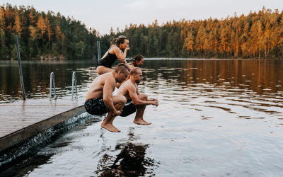 Grupp människor hoppar i vattnet från brygga