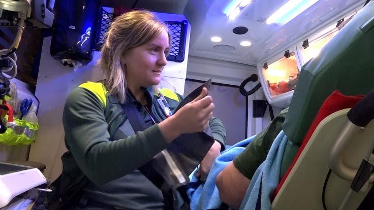 Ambulanssjuksköterska som vårdar patient i en ambulans.