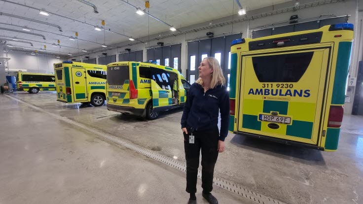 Teamledare Anna-Karin Andersson står framför ambulanserna i ambulanssjukvårdens nya lokaler i Luleå