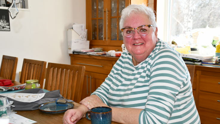 Karin sitter vid köksbordet med en kaffekopp.