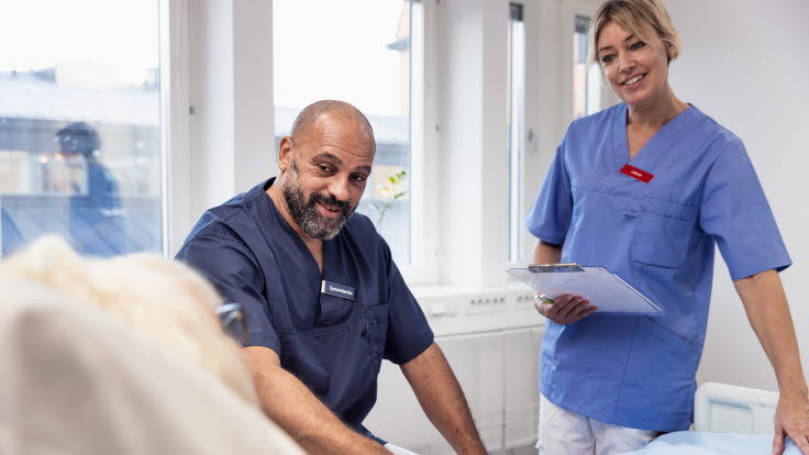 Sjuksköterska och läkare vid patient i sjukhussäng.