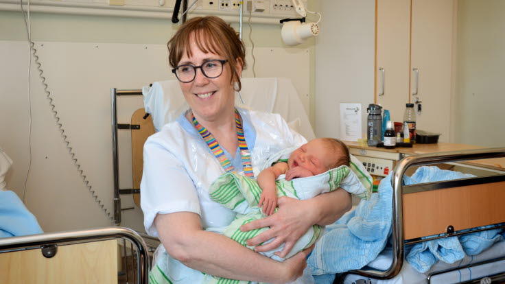 Barnmorska håller i liten bebis.