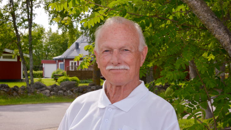 Rolf Johansson utomhus, framför en grönskande rönn.